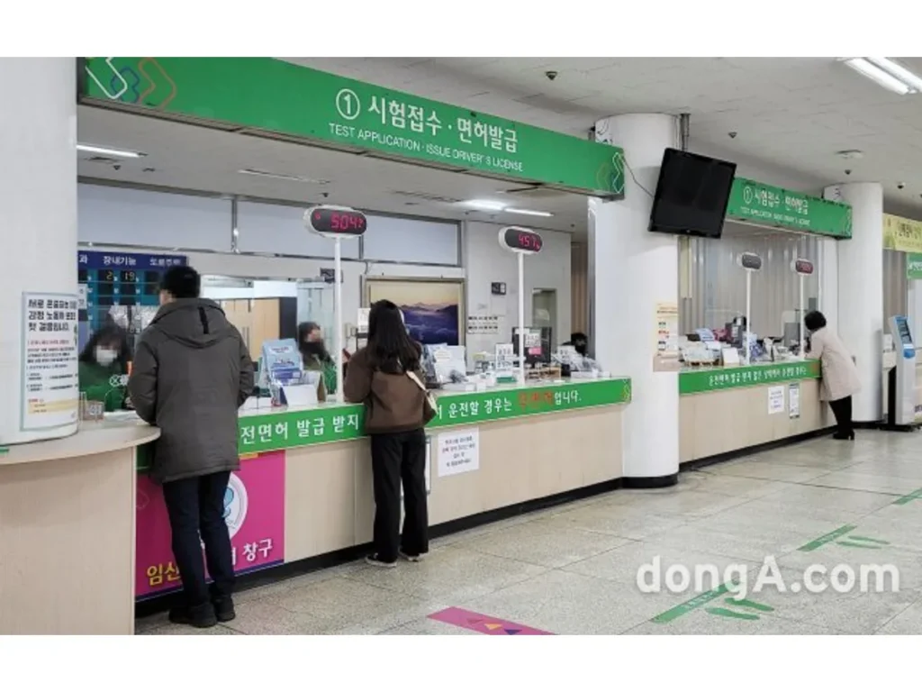 시험접수·면허발급 안내판 아래 창구에 방문객들이 서 있는 모습.
