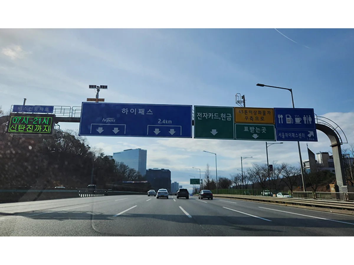 차량이 달리는 고속도로 위에 하이패스와 전자카드·현금 차로 안내판이 걸려 있다.